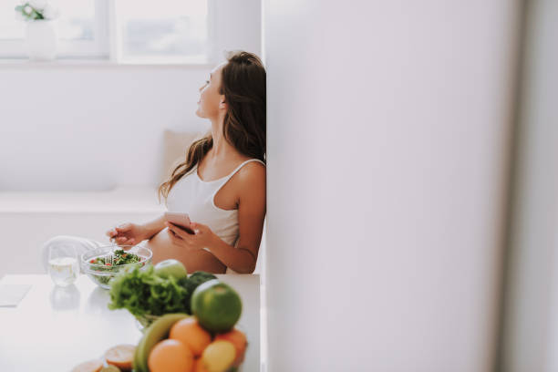 istock Future mum looking on window and sitting on chair in kitchen 1125882029