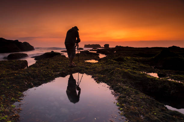 istock Silhouette Man Photographing While Standing On Rock By Sea Against Sky During Sunset 1125884457
