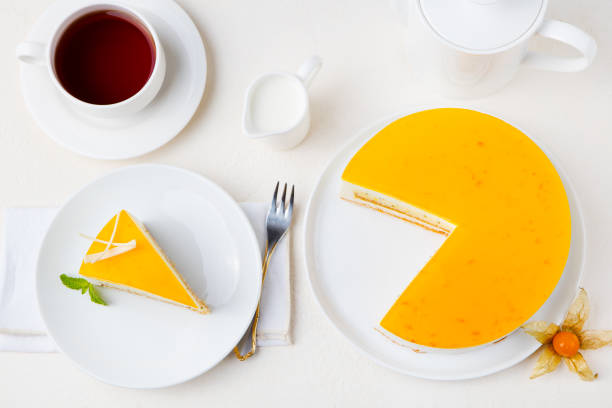 istock Passion fruit cake, mousse dessert on a white plate with cup of tea. Top view. 1125887299