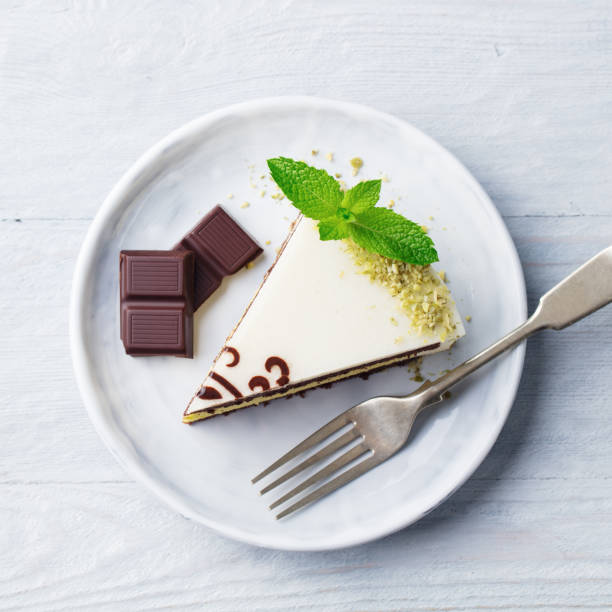 White chocolate cake with fresh mint leaf on a plate. Wooden background. Top vew.