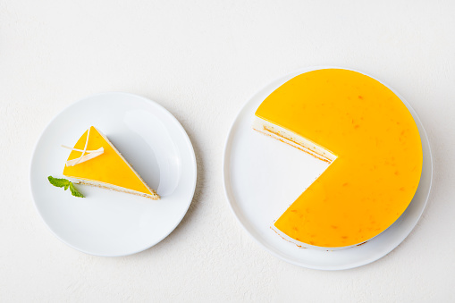 Passion fruit cake, mousse dessert on a white plate. Top view.