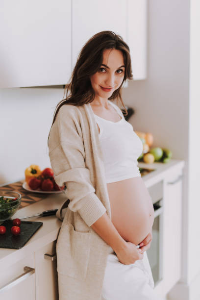 istock Expectant mother standing on kitchen and looking at camera smiling 1125889251