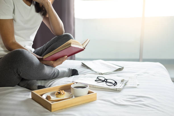 istock Low Section Of Woman Reading Book While Sitting On Bed During Morning 1125891463