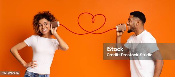 Young Black Couple With Can Phone On Orange Background Stock Photo - Download Image Now