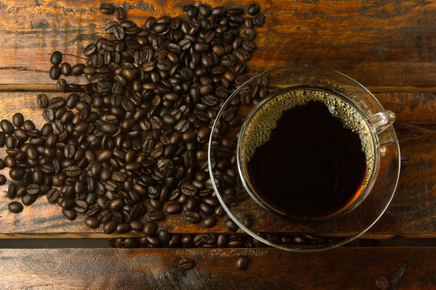 istock cup with fresh coffee and roasted beans spilled around on rustic wooden table. Top view 1125896304