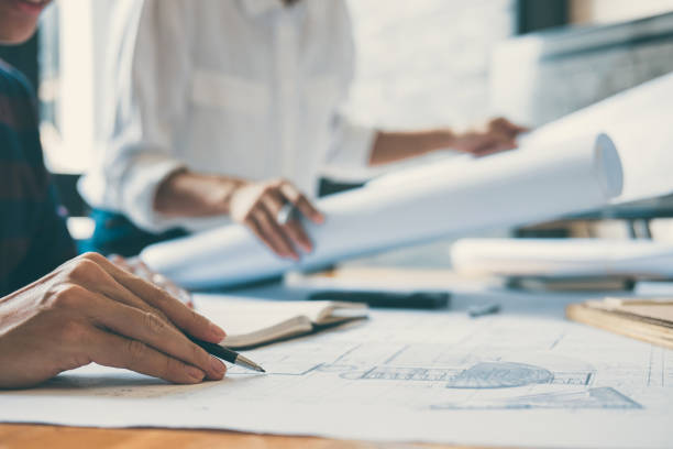 istock Midsection Of Engineers Working Over Blueprint On Table At Office 1125900317
