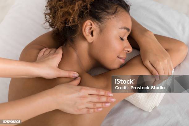 Africanamerican Woman Enjoying Shoulder Massage In Spa Stock Photo - Download Image Now