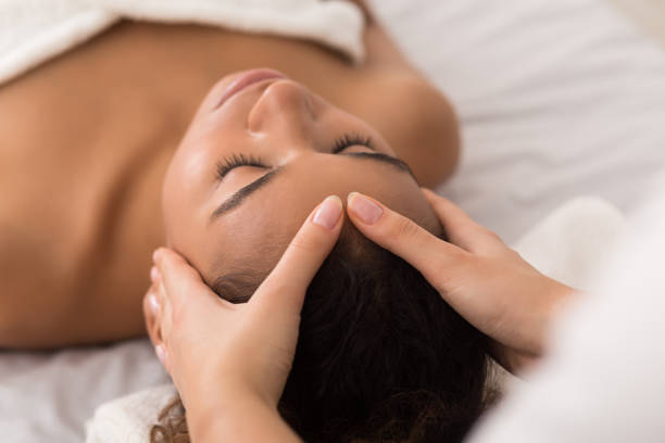 mujer disfrutando de anti masaje facial envejecimiento en el salón de spa - spa treatment fotos fotografías e imágenes de stock