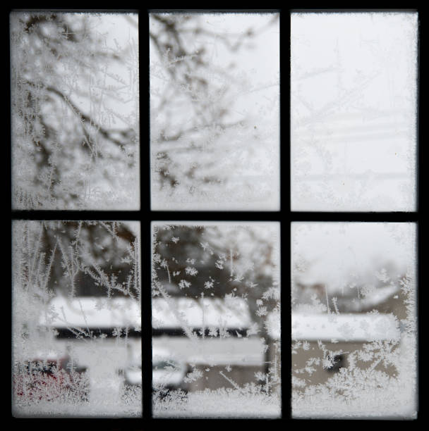 snowflakes shapes on icy window with blur outdoor winter view during storm