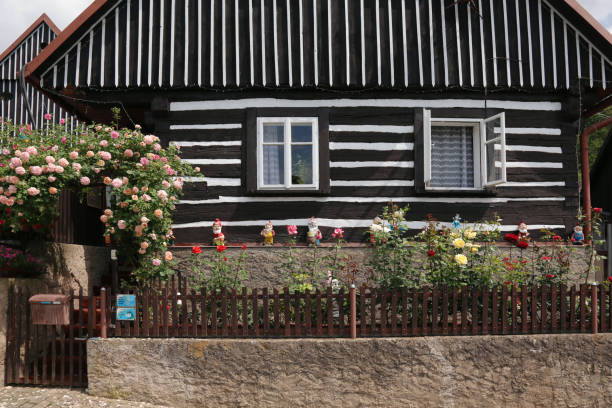 Kuks, East Bohemia, Czech Republic - June 9, 2016: Standing on the street in the small village of Kuks and looking at a traditional built timber house.  Front view, ornamental garden with dwarfs and flowering roses.