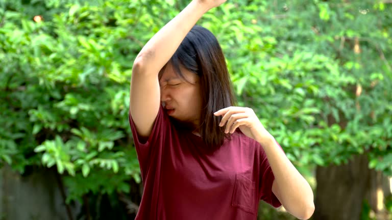 Asian young woman smells her armpits