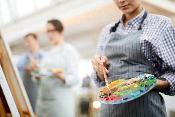 Unrecognizable Artist Holding Palette Mid section portrait of unrecognizable female artist holding palette mixing oil colors while painting picture on easel in art studio, copy space painting activity photos stock pictures, royalty-free photos & images