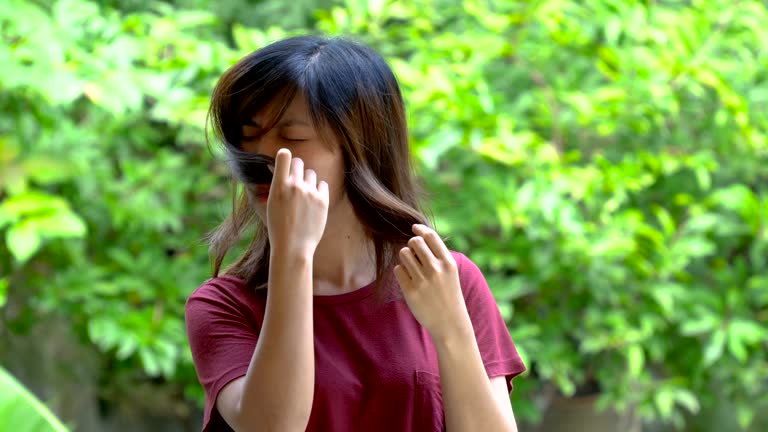 Asian young woman sniffs her own hair