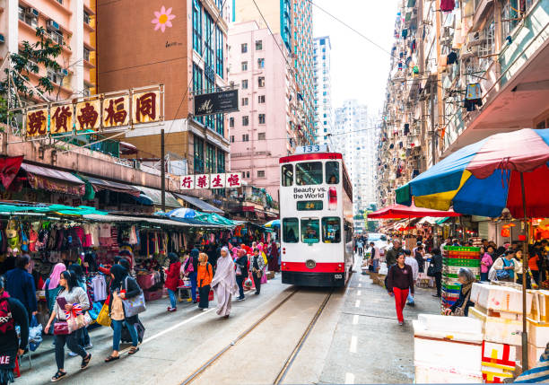 North Point Market Tram Hong Kong, China - March 27, 2016: A Hong Kong tram squeezes past shoppers and stalls at the Chun Yueng Street Market in North Point, Hong Kong public transportation photos stock pictures, royalty-free photos & images