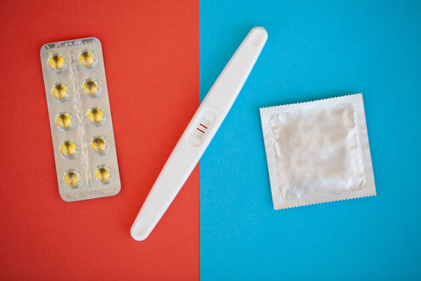 test de grossesse. le résultat est positif avec deux bandes et préservatif avec contraceptif sur fond coloré, pilule contraceptive, safe sex, santé concep - contraceptive sex education birth control pill condom photos et images de collection