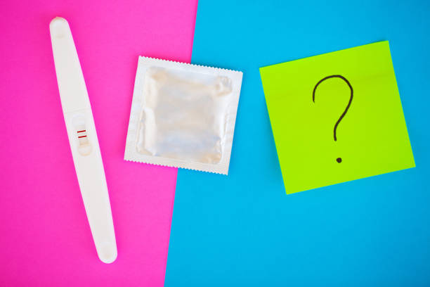 test de grossesse. le résultat est positif avec deux bandes et préservatif avec contraceptif sur fond coloré, pilule contraceptive, safe sex, santé concep - contraceptive sex education birth control pill condom photos et images de collection