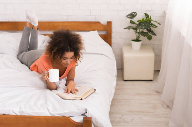 istock African-american girl reading book and drinking coffee 1125924705
