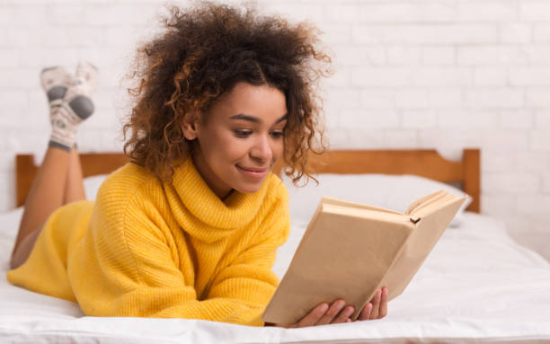 istock Relaxed girl reading book in bed at home 1125924721