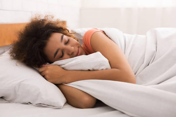 istock African-american woman sleeping and hugging white blanket 1125924728