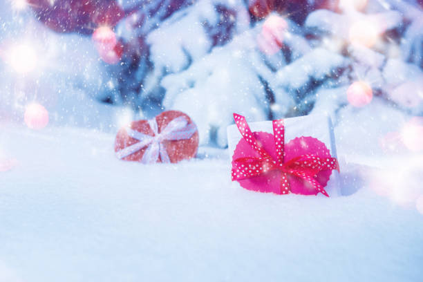istock Gift boxes with decorative heart in snowing winter forest 1125926149