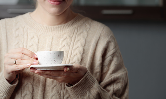 Woman in sweater with cup of coffee. Selective focus.