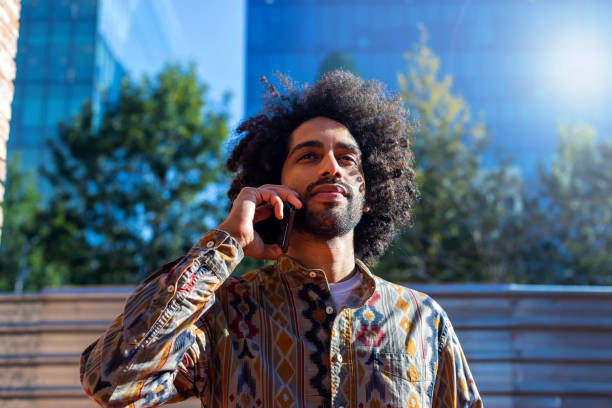 istock Front view of a handsome smiling afro man using a mobile phone while standing outdoors 1125927305