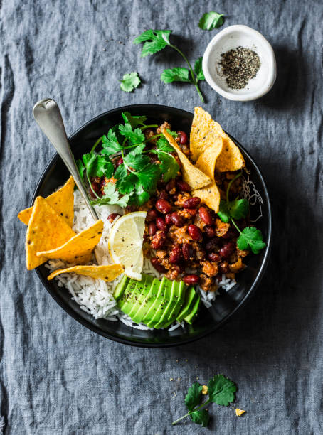 burrito rice bowl with tortilla chips, cilantro and avocado on grey background, top view - chili food bowl ready to eat imagens e fotografias de stock