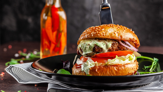 American cuisine concept. A juicy meat burger with a large klateyta, tomato, cucumber, ketchup and salad. Cooking burgers at home. Background image for a menu in restaurants or cafes. copy space