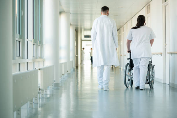 doctor and nurse pushing wheelchair with patient in hospital - healthcare and medicine nurse doctor general practitioner imagens e fotografias de stock