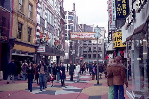 London, England, UK, 1974. The famous Carnaby Street in London. First pedestrian zone in Europe. Furthermore: shops, boutiques, tourists advertising signs and pedestrians.