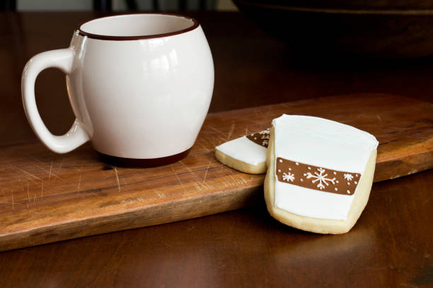 Gingerbread cookies decorated with latte coffee cups on a wooden board with a ceramic mug.