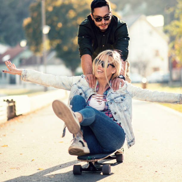 istock Young man pushing his girlfriend on skateboard 1125939765