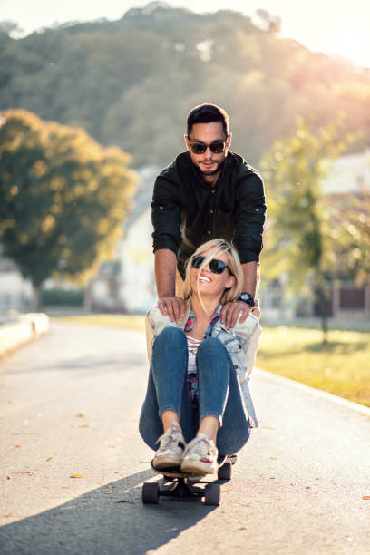 istock Young man pushing his girlfriend on skateboard 1125939766