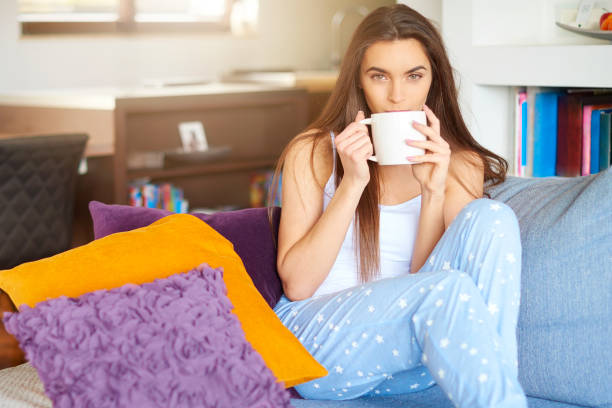 istock Beautiful young woman drinking morning tea while sitting on couch at home 1125939927