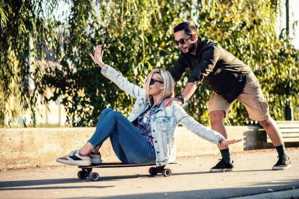 istock Young man pushing his girlfriend on skateboard 1125941303