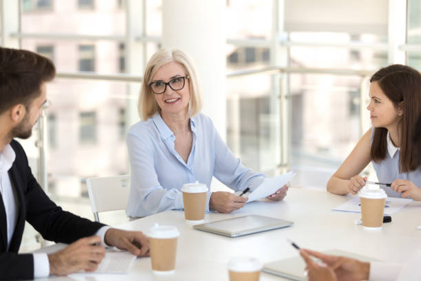 istock Mature team leader sitting with colleagues at briefing 1125941832