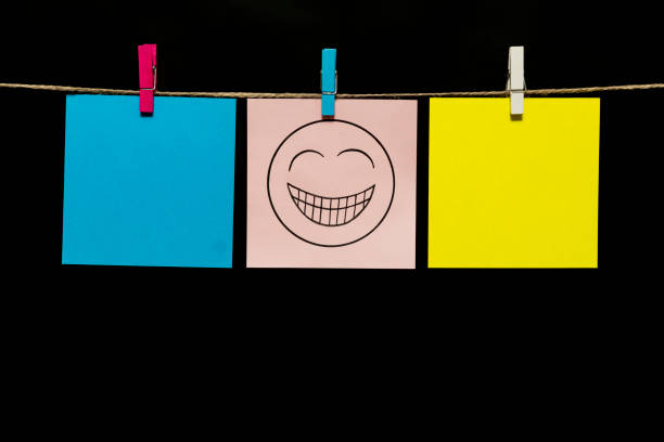 istock Copy space. Three multicolored stickers. On gray page on the face is an expression of gaiety. Stickers are attached to the rope with clothespins. 1125944542