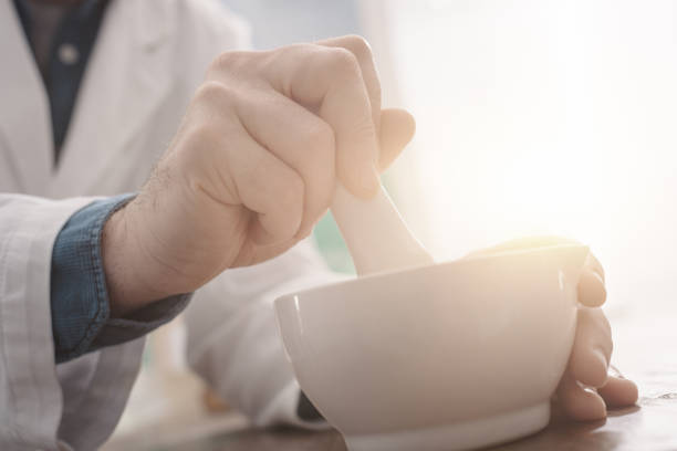 Professional pharmacist grinding a medical preparation using a mortar and pestle, pharmacy and medicine concept, hands close up