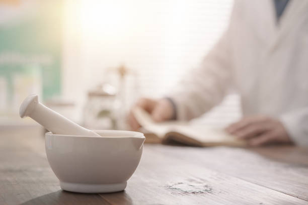 Professional pharmacist grinding a medical preparation using a mortar and pestle, pharmacy and medicine concept, hands close up