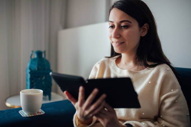 istock Woman reading e book at home 1125947113