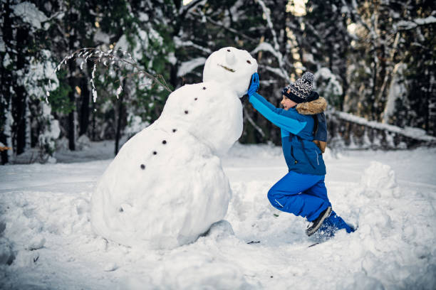 istock Little boy building a snowman on a winter day 1125947132