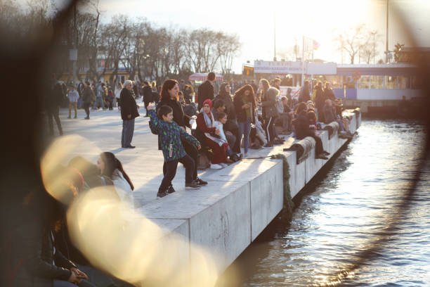 Istanbul, Turkey - January 29, 2019: Youth people are sitting at sea coast of The Kadikoy with beautiful reflections on the water at sunset.kadikoy