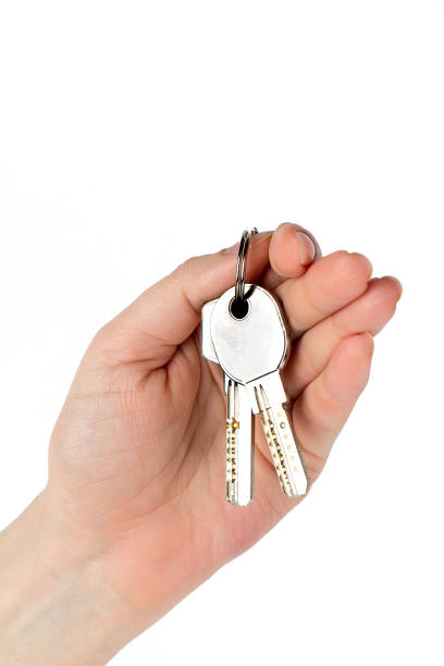 istock Female hand holds two keys isolated on white background 1125947239