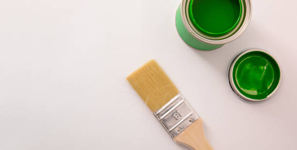 istock Open green acrylic paint canister on white table and paintbrush 1125947489