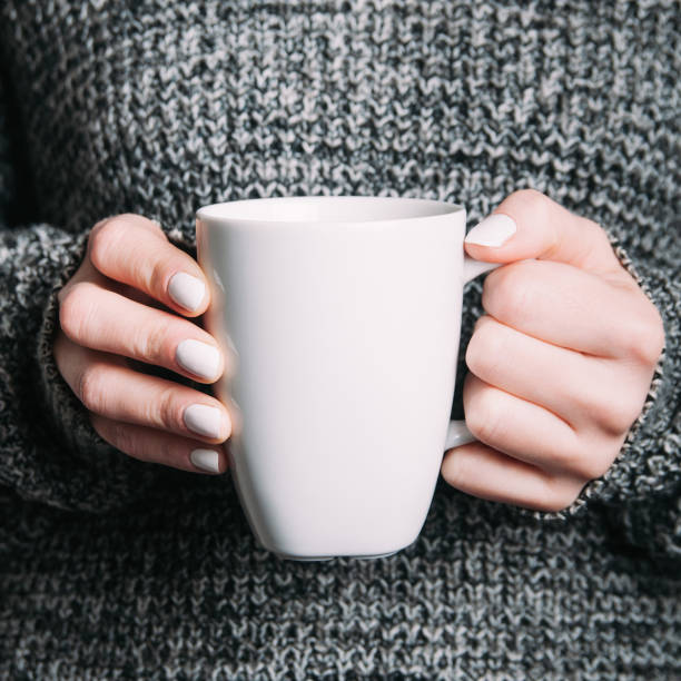 istock A woman holding a white mug in her hands. Template for design or text 1125948049