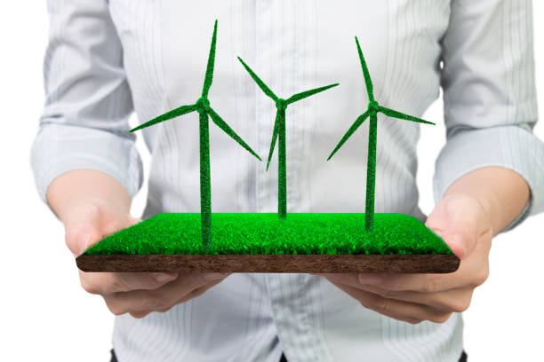 Green energy supply and solution concept, woman hands holding a turf tile with grass in wind turbines shape, front view, isolated on white.