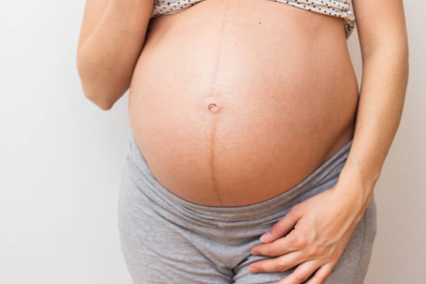 femme enceinte debout à côté de mur - kit mains libres photos et images de collection