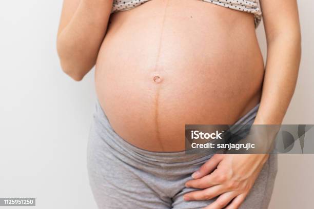 Pregnant Woman Standing Next To Wall Stock Photo - Download Image Now - Abdomen, Adult, Adults Only