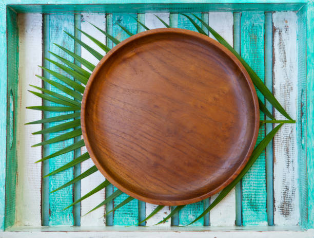 istock Wooden plate with palm leaf on colorful background. Copy space. Top view. 1125957492