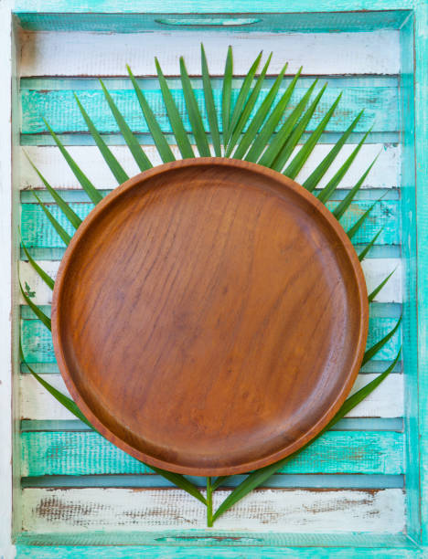 istock Wooden plate with palm leaf on colorful background. Copy space. Top view. 1125957500